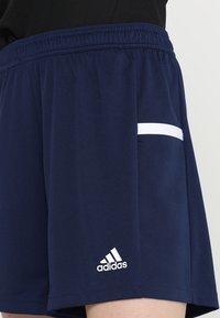 Pantalones cortos deportivos azul marino con bolsillo de acento blanco. Hechos de un tejido suave, con una cintura elástica y un pequeño logo blanco.