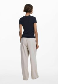T-shirt côtelé bleu marine à manches courtes, associé à un pantalon large à rayures beige clair. Tissu lisse avec une coupe décontractée.