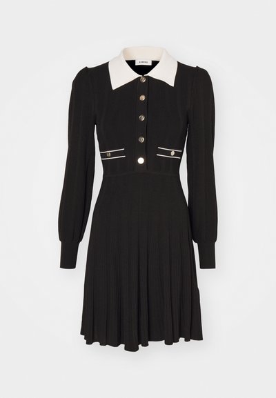 Svart stripete kjole med lange ermer, hvit krage og knappelukking foran, med hvite akzentstriper og detaljer i sølvfargete knapper.