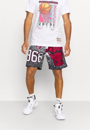 Hombre que usa zapatillas blancas, calcetines blancos, shorts de baloncesto en blanco y negro con el logo de los Bulls en rojo, y una camiseta blanca de baloncesto de los Spurs.