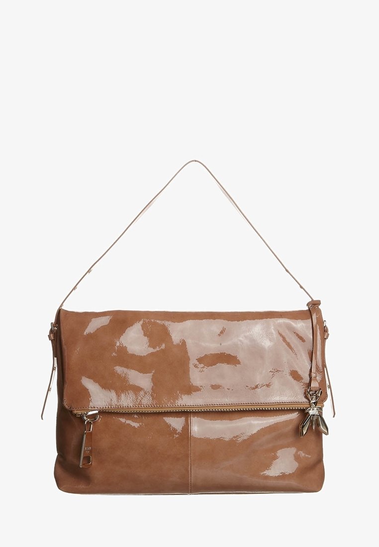 Braune Lederhandtasche mit glänzender Oberfläche, ausgestattet mit einer umklappbaren Klappe, goldenen Beschlägen und einem abnehmbaren Charme-Akzent.