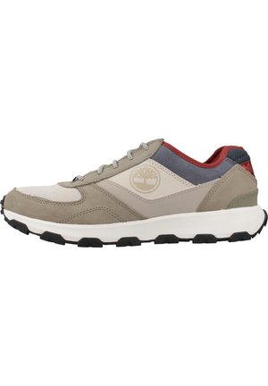 Beige Sportschuh aus einer Mischung aus Wildleder und Mesh-Materialien. Verfügt über graue und rote Akzente, runde Schnürsenkel und eine robuste Gummisohle in Schwarz.