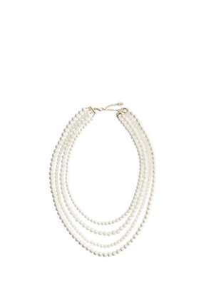 Collier de perles blanches à quatre rangs avec fermoir en or et chaîne ajustable sur fond blanc.
