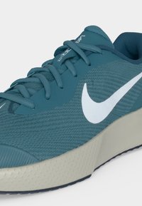 Μπλε αθλητικό παπούτσι Nike με λευκό λογότυπο Swoosh, σχέδιο με κορδόνια και υφή ανοιχτόγριζας σόλας.