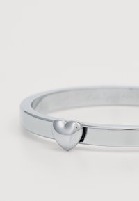 Silver bangle bracelet featuring a smooth heart accent, with a polished finish and a minimalist design.