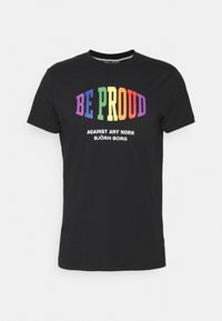 Czarny bawełniany t-shirt z napisem "BE PROUD" w kolorach tęczy oraz "AGAINST ANY NORM BJÖRN BORG" w białym kolorze, zaokrąglony dekolt i krótkie rękawy.