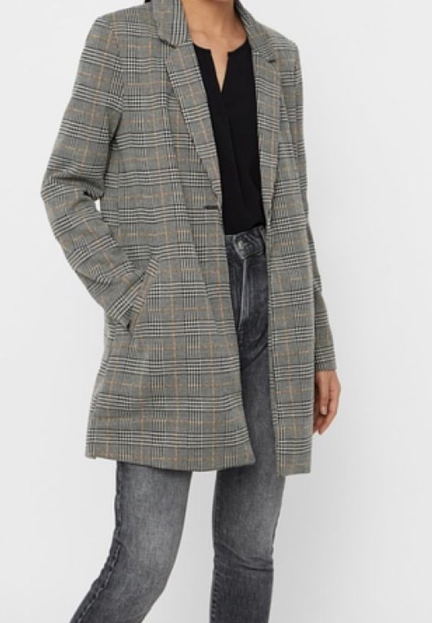 Šedý kostkovaný blazer se strukturovaným designem, jednobarevný přední díl a dvě boční kapsy. Kombinováno s černým topem a šedými džíny.