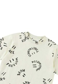 Vit t-shirt med kort ärm som har svart, kurvad text med ord som "fred" och "frihet", som skapar ett oregelbundet mönster över tyget.