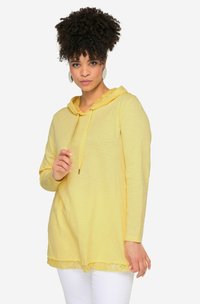 Žlutá mikina s dlouhým rukávem s krajkovým lemem na spodním okraji. Má šňůrku u krku a měkkou, texturovanou látku.