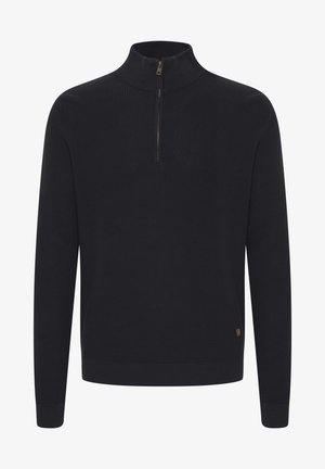 Zwarte geribbelde gebreide trui met een hoge kraag en een rits aan de voorkant. Heeft lange mouwen en een klein bruin label aan de zoom.