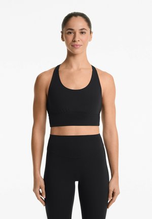 Top sportivo nero a maniche corte con scollatura rotonda, spalline larghe e arricciature nella zona centrale, abbinato a leggings neri a vita alta.