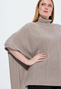 Beżowy, oversize golf z prążkowanym splotem i opadającymi ramionami. Zawiera pionowe szwy, półrękawy i luźny fason.