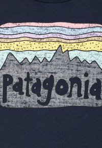 Marineblauw T-shirt met een grafisch ontwerp van kleurrijke berglagen en de tekst "Patagonia" in een zwart, speels lettertype.