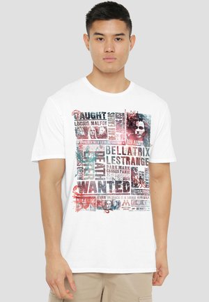 Young man wearing a white T-shirt with a collage of wanted posters featuring characters and text from Harry Potter.