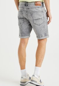 Grå denimshorts med uppvikta fållar, bakfickor och en brun läderlapp vid midjan. Designade för en avslappnad passform.