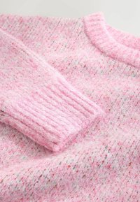 Rosa stickad tröja med en mjuk textur, ribbad ärm och flerfärgade fläckar i tyget. Rund halslinning och en avslappnad passform.