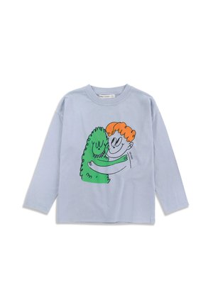 Chemise bleu clair à manches longues avec un dessin animé représentant une personne aux cheveux orange embrassant un monstre vert souriant.