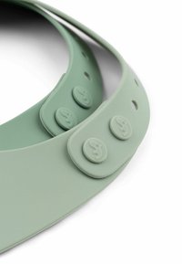 Grøn silikone skygge med en glat overflade, der har to runde knapper og flere huller for justerbar pasform.