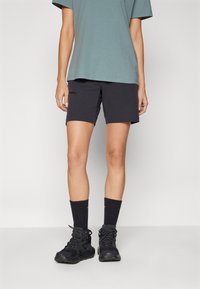 Black shorts with a zippered pocket, paired with a teal T-shirt, black socks, and black hiking shoes. Simple design and functional materials.