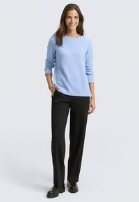 Jasnoniebieski sweter z okrągłym dekoltem, długimi rękawami, w połączeniu z czarnymi spodniami i czarnymi botkami. Gładka tekstura, luźny krój.