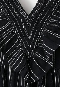 Tissu noir à rayures verticales blanches, présentant un motif cousu en forme de V et des détails froncés au niveau de l'encolure.