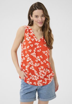 Top senza maniche rosso floreale con scollatura a V, presenta un motivo di fiori bianchi e una vestibilità comoda. Abbinato a pantaloni corti in denim. Tessuto morbido.