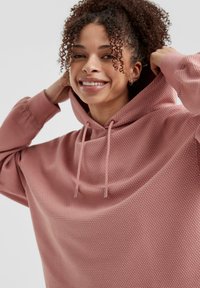 Oversized roze hoodie van textuurstof, met een trekkoord in de nek en geribbelde boorden. Gladde afwerking, casual ontwerp en een relaxte pasvorm.
