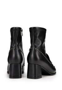 Czarne botki sięgające kostki, wykonane z gładkiej skóry, z obcasem w kształcie słupka i ozdobnymi ćwiekami po bokach. Zamek błyskawiczny z tyłu.