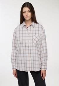 Camicia a quadri chiara in tonalità beige e marrone, con taschino sul petto, maniche lunghe e una vestibilità comoda.