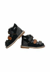 Sandales orthopédiques pour enfants en cuir noir avec des sangles réglables marron et noir et des semelles beiges cousues.