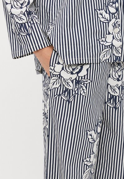 Navy and white striped fabric featuring floral patterns. Loose-fitting design with a pocket at the waist. Soft texture and lightweight material.