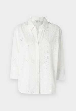 Chemise blanche à boutons, en tissu brodé avec des découpes en œillets, dotée d'un col et de manches trois-quarts.