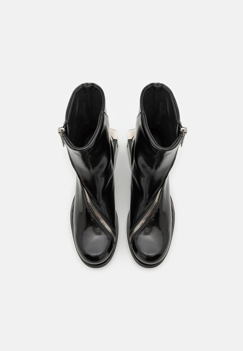 Zwarte gepatenteerde leren enkelboots met een zijrits en een strak, minimalistisch ontwerp. De binnenkant heeft een zachte zwarte voering.
