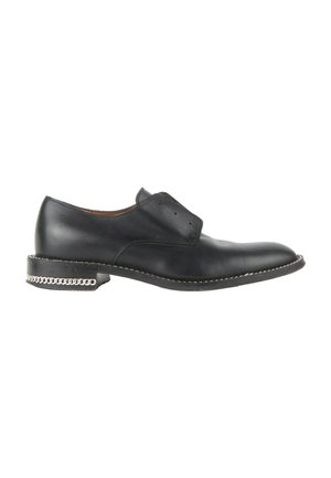 Chaussure habillée en cuir noir avec un petit talon, détail chaîne argentée, œillets sans lacets, et coutures blanches le long de la semelle.