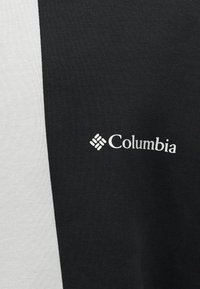 Λογότυπο Columbia σε ύφασμα διχρωμίας μαύρο και λευκό, πιθανώς κομμάτι ρούχου ή εξωτερικού ρούχου.