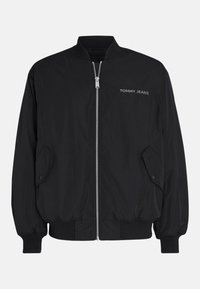 Blouson bomber noir zippé avec poignets et ourlet côtelés, poches à rabat, et logo "TOMMY JEANS" sur la poitrine gauche.