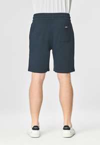 Pantaloni corti blu navy con elastico in vita, due tasche laterali, una tasca posteriore e un piccolo logo accento vicino alla tasca. Tessuto in cotone misto.