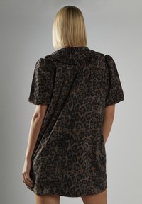Sukienka w panterkę w brązowo-czarnym kolorze, z krótkimi bufkami i falbaniastym kołnierzem, o luźnym, swobodnym kroju.