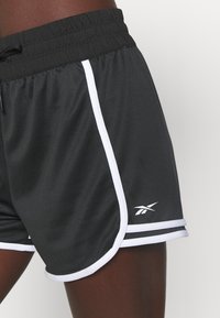 Svarta träningsshorts med dragsko i midjan, med kontrasterande vita sidosträck och en liten logotyp på underbenet. Lättvikts tyg.