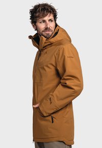 Brown waterproof jacket with a high collar and adjustable hood. Features zippered front and side pockets, and a sleek, streamlined design.