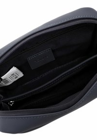 Tumši zila zipu somiņa no gludas ādas ar teksturētu iekšpusi, kurā ir divas nodalījumi un iekšpusē atzīmes etiķete.