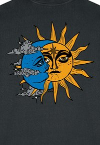 Un tissu noir présente un design illustré d'une lune bleue avec un visage, entourée de nuages gris, et d'un soleil jaune avec des rayons saillants.