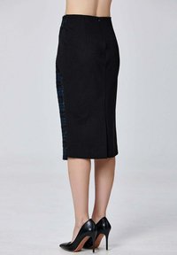 Jupe crayon noire avec un panneau latéral texturé bleu, longueur genou, fermeture éclair au dos, associée à des chaussures à talons hauts noires.