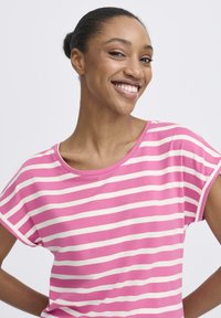 Triibuline t-särk roosade ja valgete horisontaalsete joontega, pehme puuvillane kangas, ümar kaelus ja lõdvalt istuv lõige. Lühikesed varrukad, mille servad on üleskeeratud.