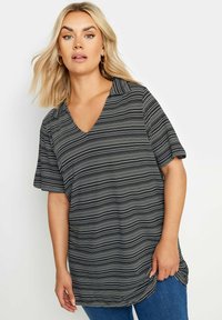 Camiseta de manga corta a rayas en blanco y negro con cuello en V y corte relajado, fabricada en una tela suave y ligera, con un dobladillo ligeramente curvado.