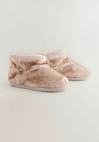 Flauschige beige Hausschuhe mit weicher Textur, niedriger Knöchelhöhe und abgerundetem Zeh. Die Sohle hat eine einfache, schmale Einfassung.