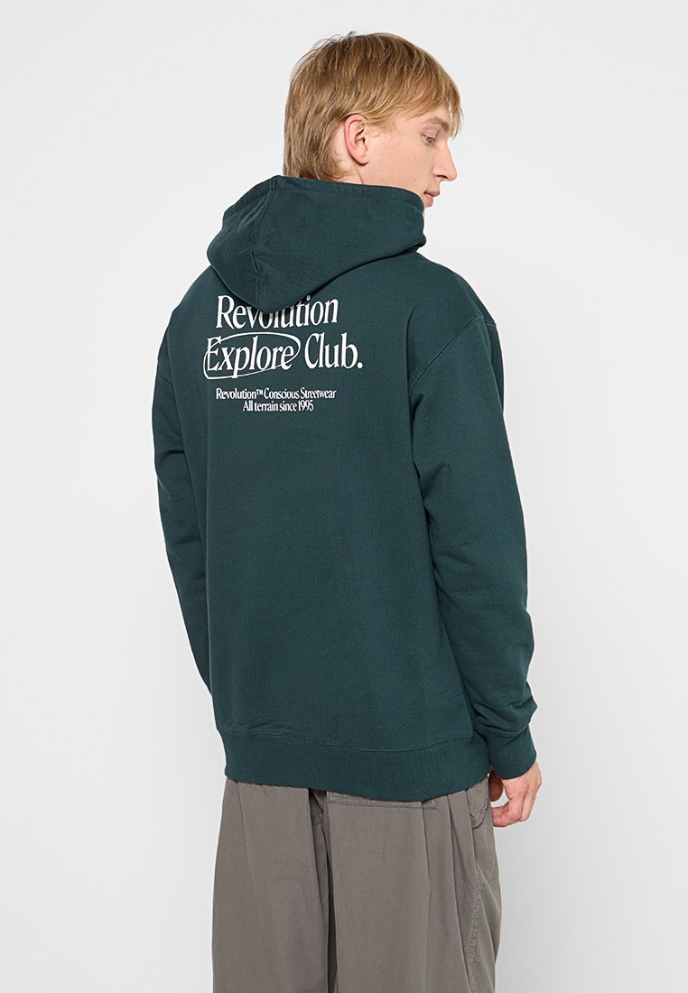 Mörkt grön huva sweatshirt med en avslappnad passform, med vit text på baksidan, samt ribbade manschetter och nederkant. Mjuk, bomullsmix.