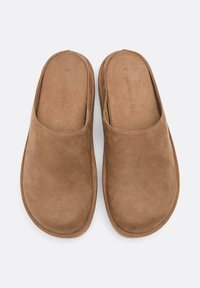 Smeđe suknene papuče za slip-on s glatkom teksturom i zaobljenim dizajnom prsta. Unutrašnjost ima mekanu oblogu i suptilne detalje šivanja.