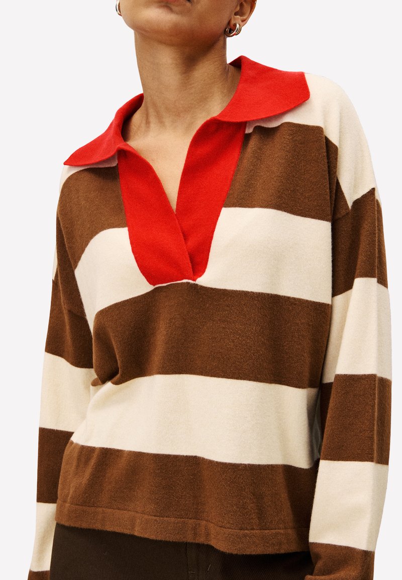 Gestreepte pullover in bruin, crème en rood. Kenmerkt zich door een kraag en een ontspannen pasvorm. Zachte textuur, opvallende verticale strepen en ribgebreide boord.