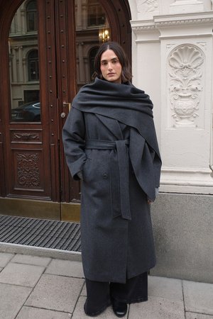 Temno siva dolga plašč iz volne, z ovito zasnovo, širokimi rokavi in pasom. Oblečen je čez temne hlače in škornje.